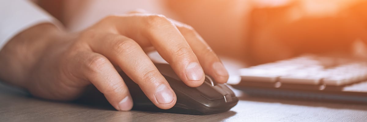 Close up of man's hand using computer mouse with blurred background
